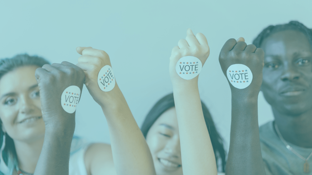 A picture of young people holding their hands up with stickers that read "vote".