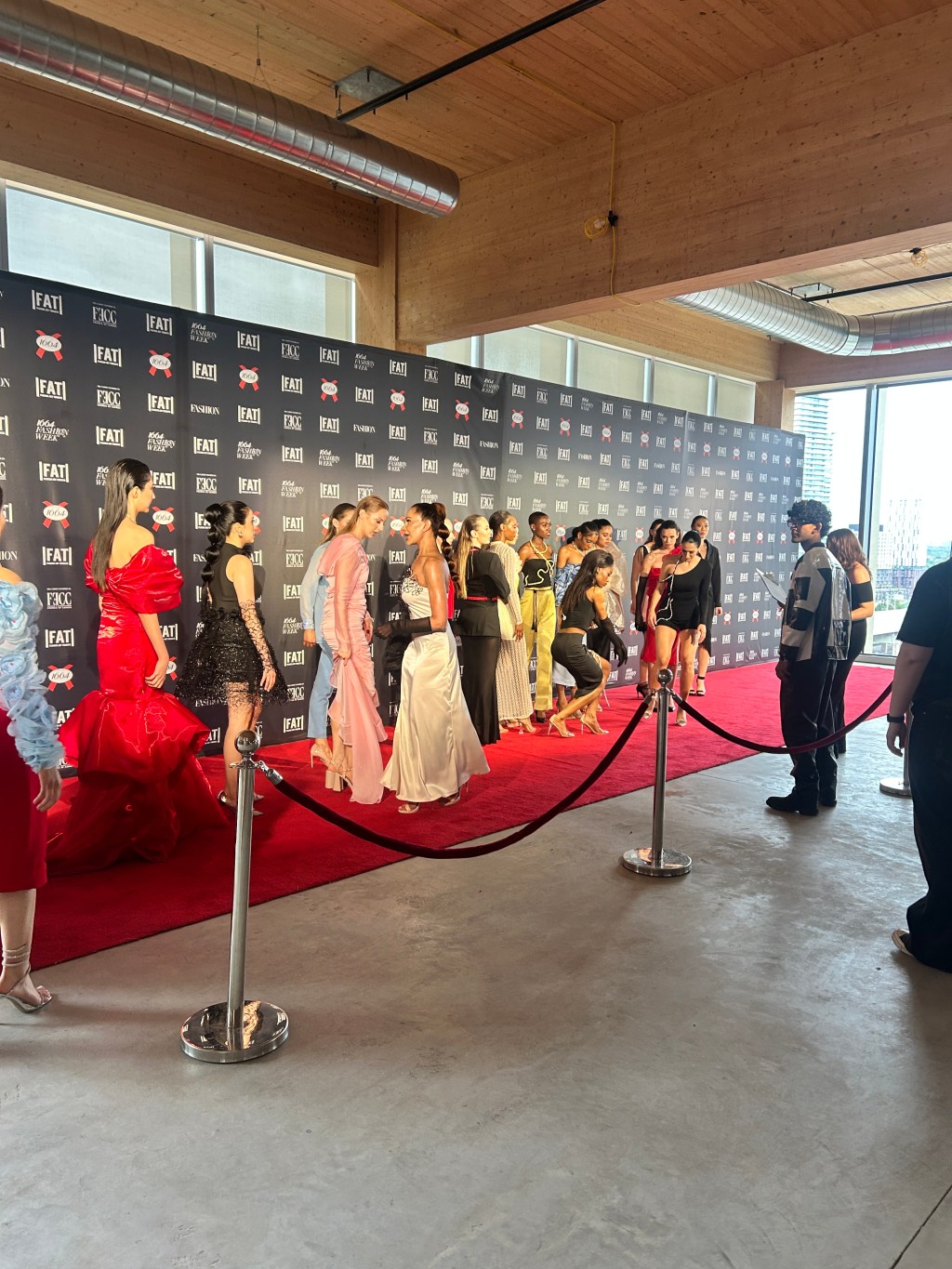 A group of models posed in fancy clothes on a red carpet at Fashion Art Toronto's Spring Summer 2025 show.